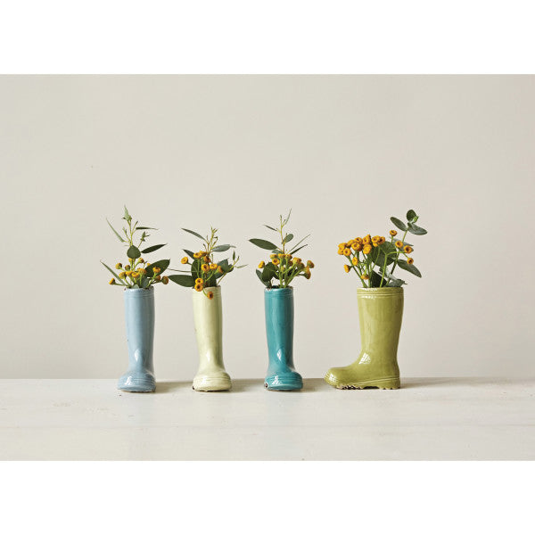 A set of four small stoneware vases in the shape of boots with distressed finishes and various colors.